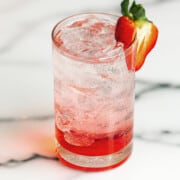 strawberry italian soda with a strawberry garnish on a marble counter